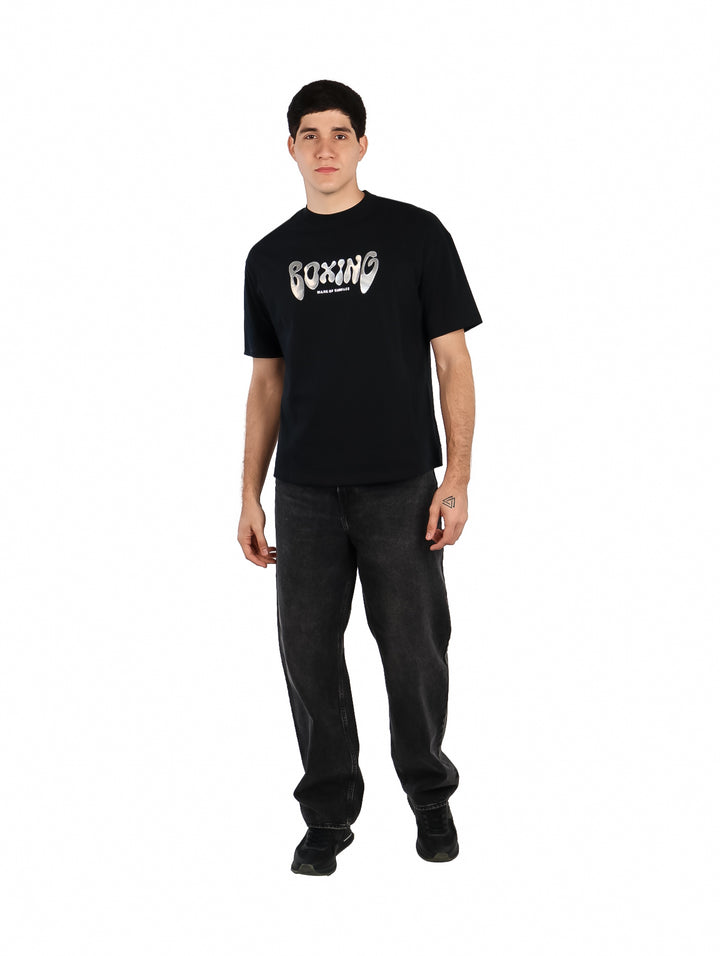 Hombre vistiendo playera oversize color negro con estampado blanco de la palabra BOXING en el pecho.