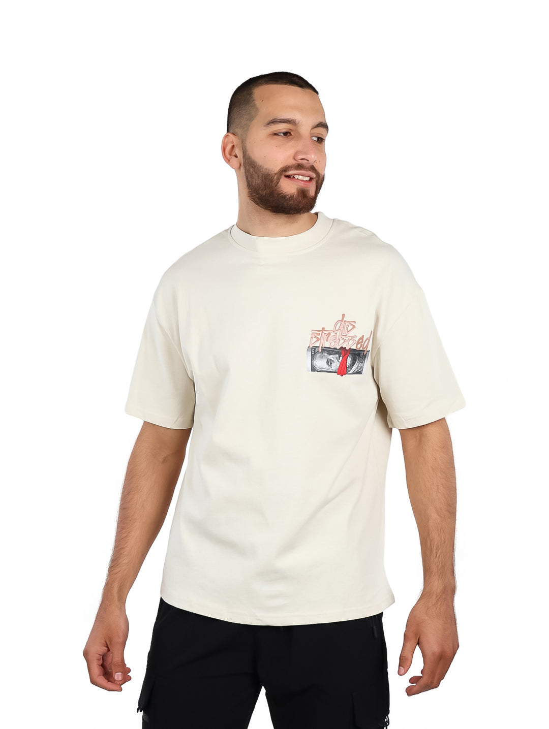 Hombre vistiendo una playera oversize de color beige con un pequeño gráfico en el pecho.
