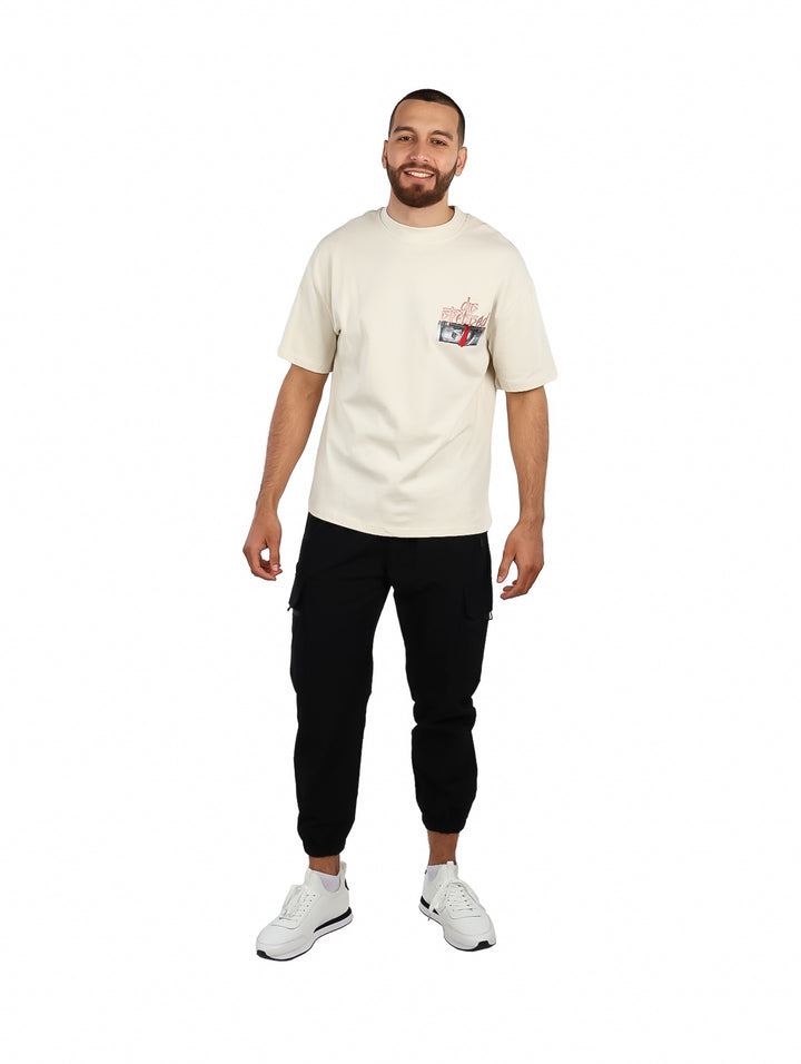 Hombre vistiendo una playera oversize de color beige con un pequeño gráfico en el pecho.
