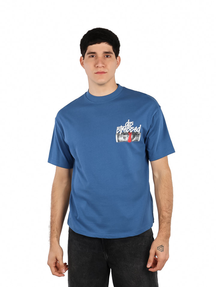 Hombre vistiendo playera azul oversize de manga corta con estampado gráfico en el pecho.