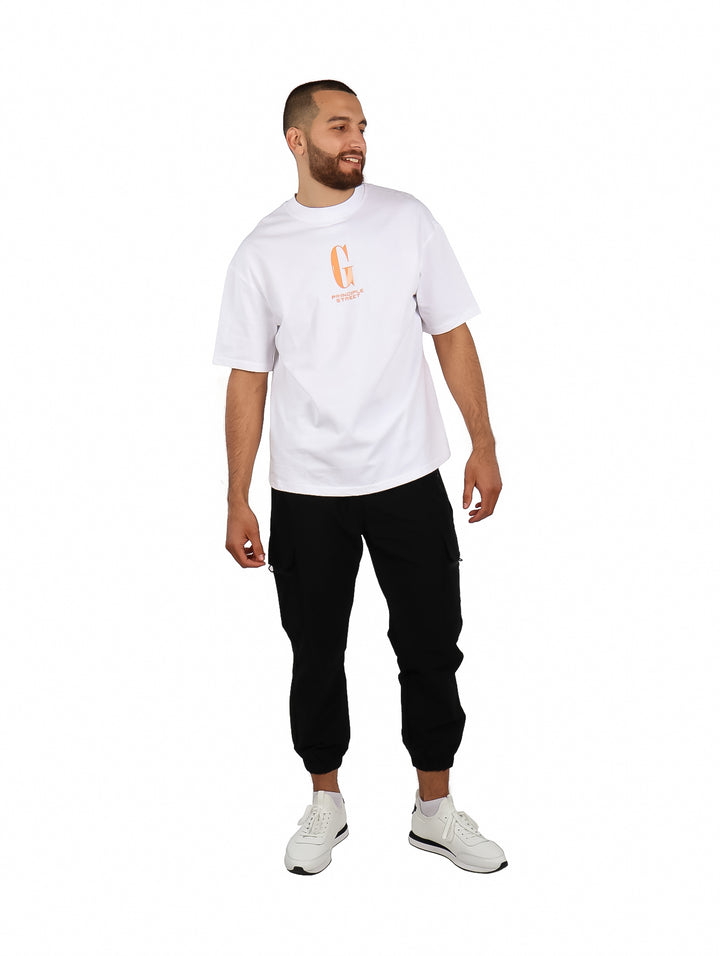 Hombre vistiendo playera blanca oversize de manga corta con un gráfico naranja en el pecho.