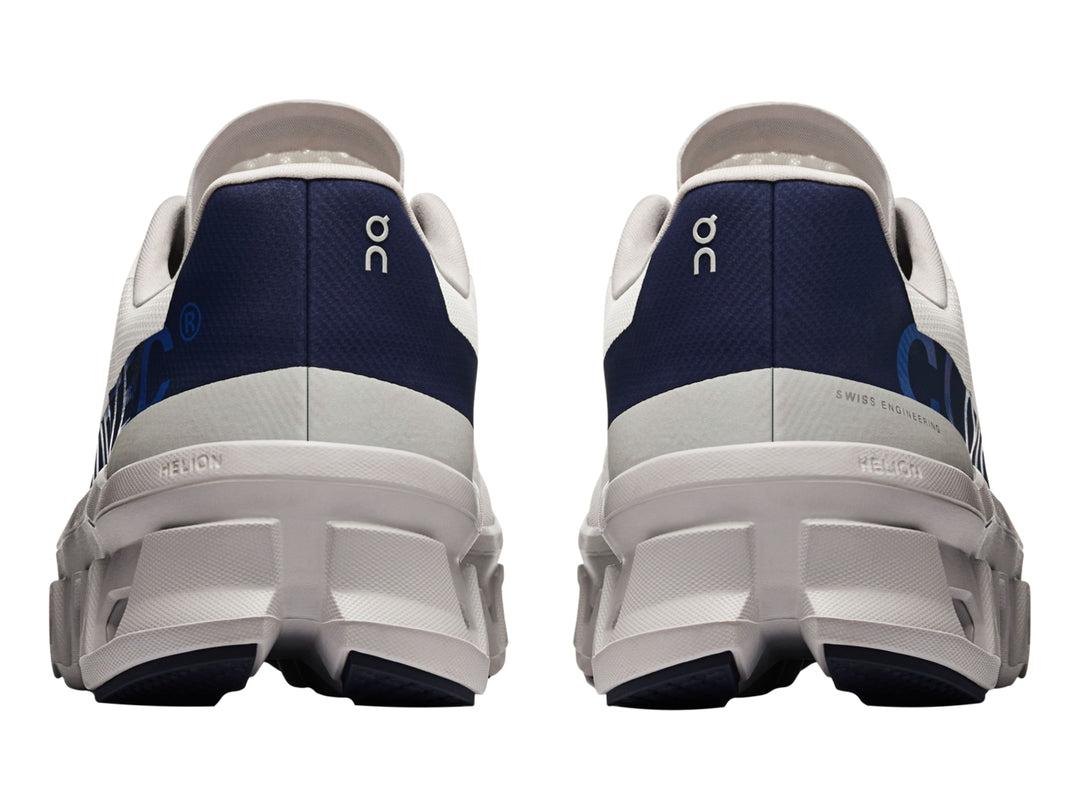 Tenis deportivos ON Cloudmonster en color marfil con detalles en azul marino y suela blanca estructurada.