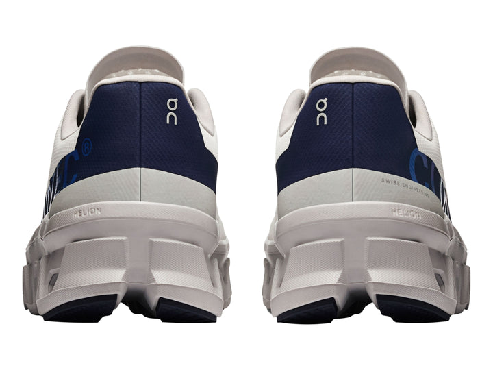 Tenis deportivos ON Cloudmonster en color marfil con detalles en azul marino y suela blanca estructurada.