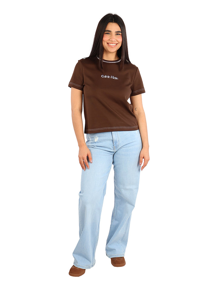 Mujer vistiendo una camiseta ajustada color café de Calvin Klein con costuras blancas contrastantes.