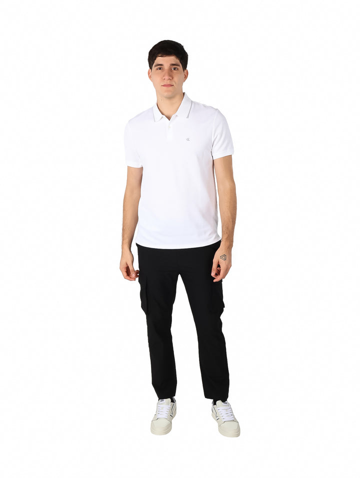 Hombre vistiendo una playera polo blanca de manga corta de la marca Calvin Klein.