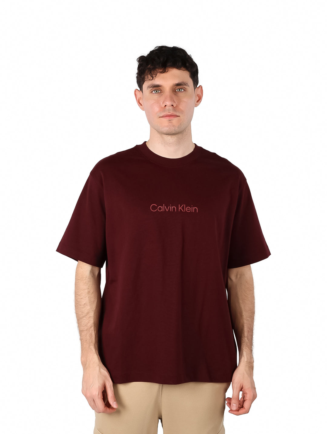 Hombre vistiendo una camiseta de manga corta color marrón oscuro con el logo de Calvin Klein en el pecho.