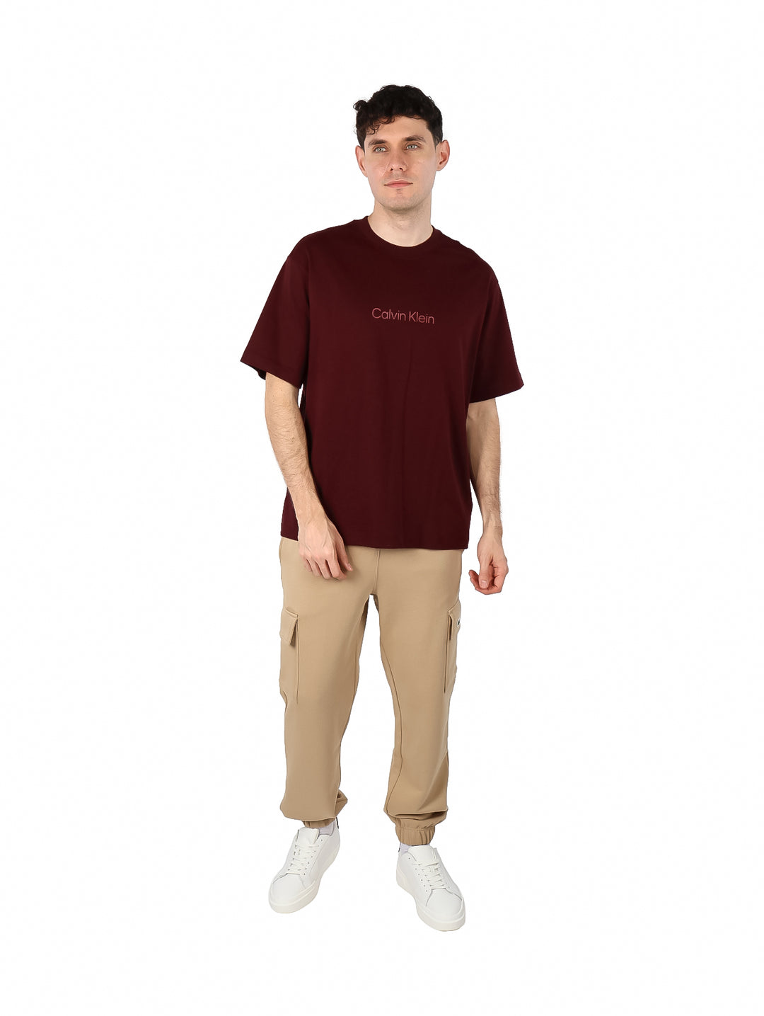Hombre vistiendo una camiseta de manga corta color marrón oscuro con el logo de Calvin Klein en el pecho.