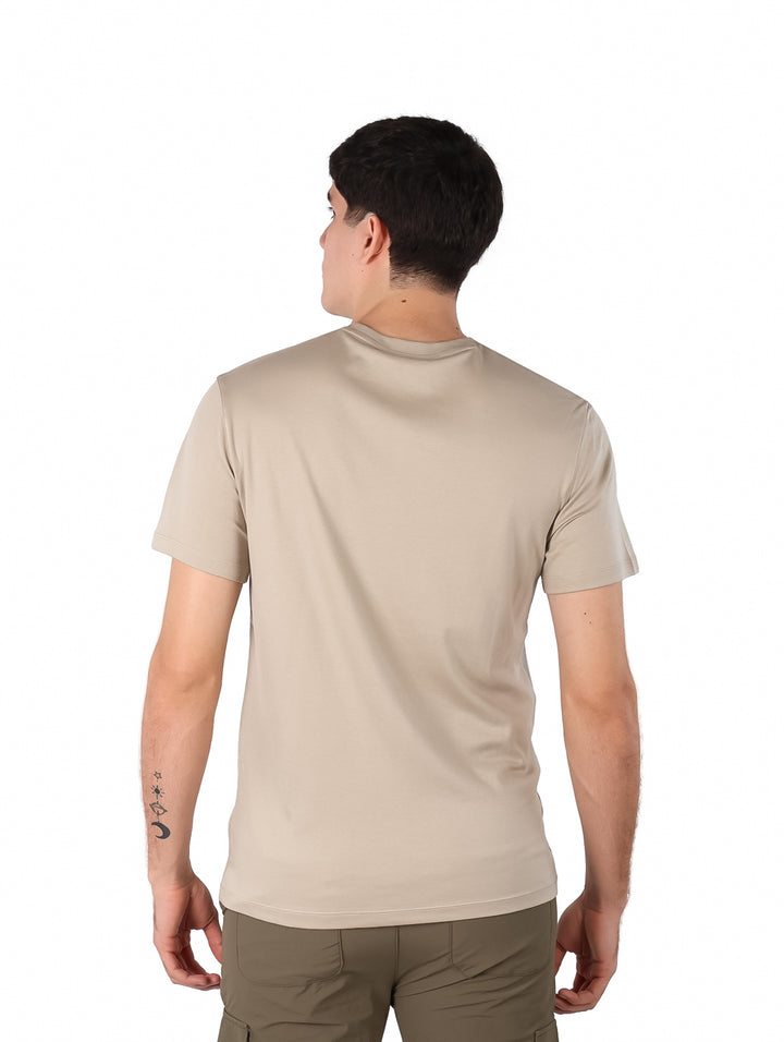 Hombre vistiendo una camiseta de manga corta color beige con cuello redondo.