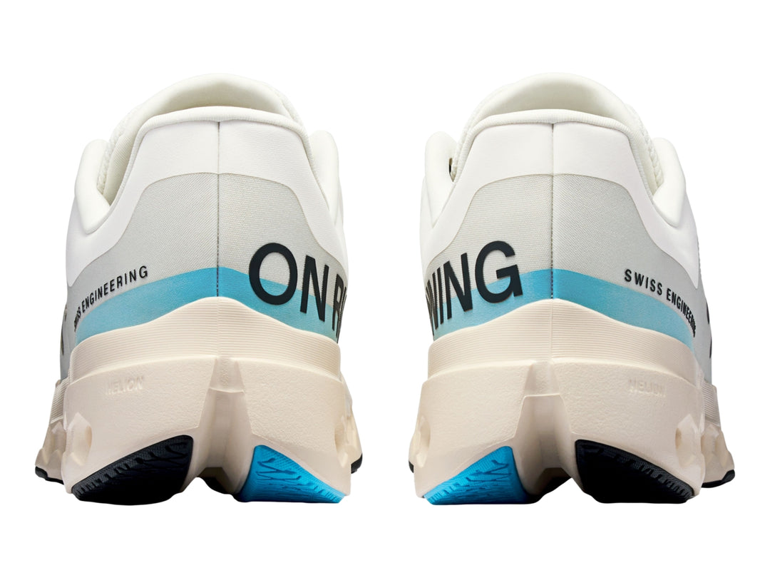 Tenis deportivos On Cloudsurfer Next en color marfil con detalles en azul claro y suela blanca perforada.