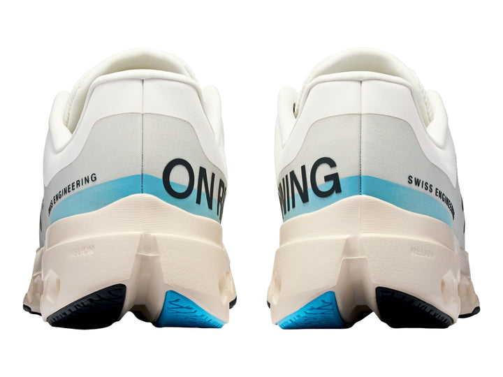 Tenis deportivos On Cloudsurfer Next en color marfil con detalles en azul claro y suela blanca perforada.