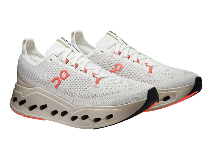 Tenis deportivos On Cloud color marfil con detalles en salmón y suela amortiguada hueca.