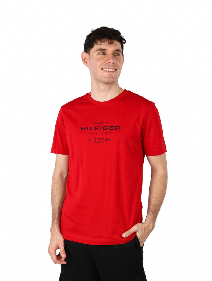 Hombre vistiendo una camiseta roja de manga corta con logotipo de Tommy Hilfiger en el pecho.
