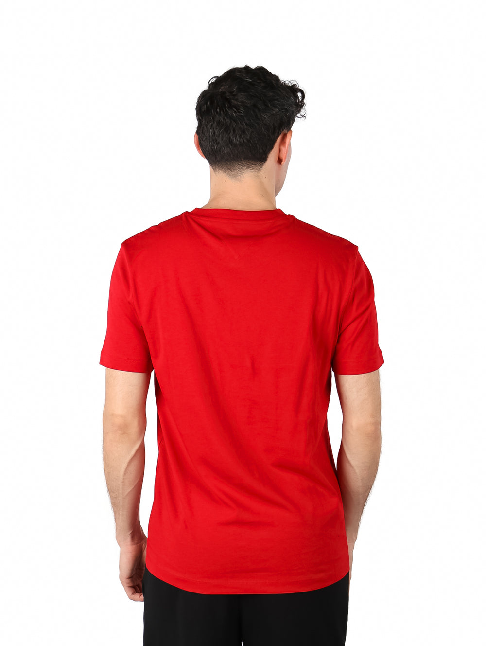 Hombre vistiendo una camiseta roja de manga corta con logotipo de Tommy Hilfiger en el pecho.