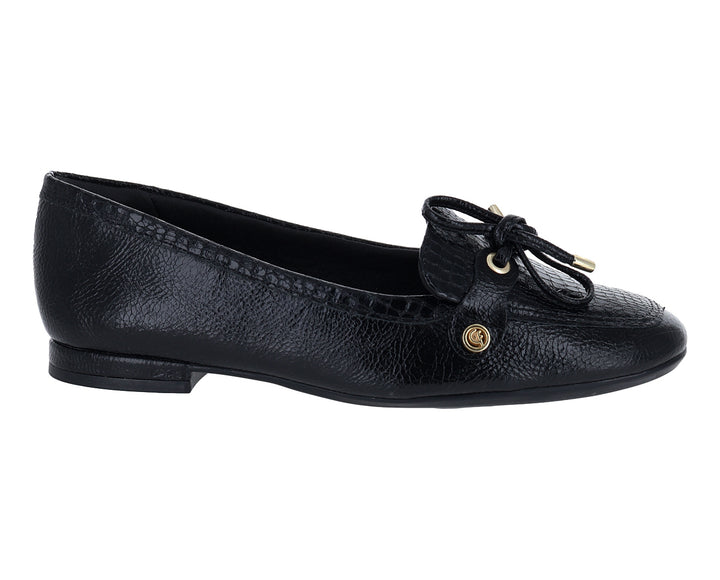 Mocasín negro para mujer con textura granulada y detalle de moño dorado en la parte superior.