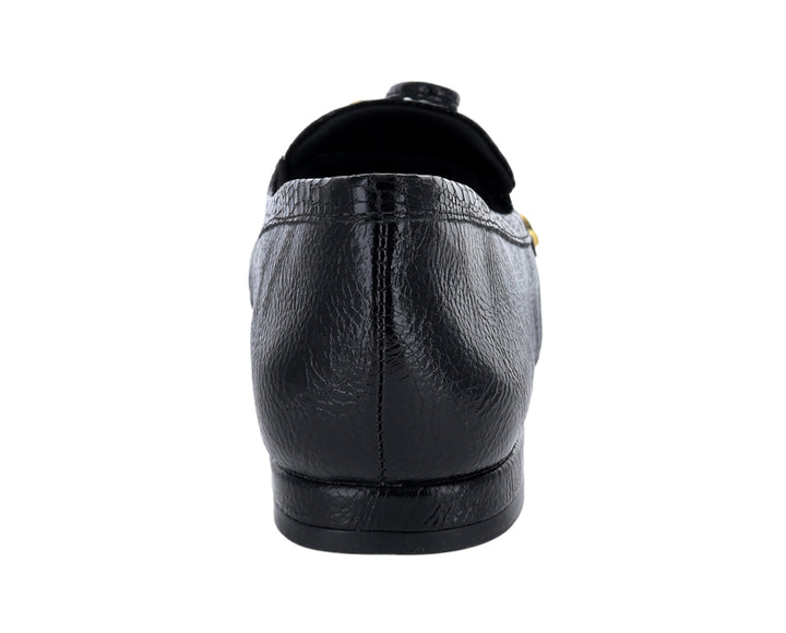 Mocasín negro para mujer con textura granulada y detalle de moño dorado en la parte superior.