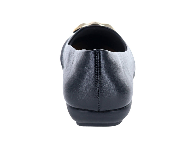 Zapato plano tipo ballerina color negro con un adorno dorado en la parte frontal.