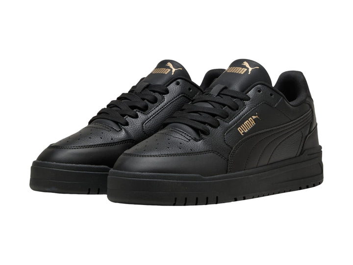 Tenis PUMA Shuffle Downtown color negro con suela gruesa y detalles dorados, vista lateral.