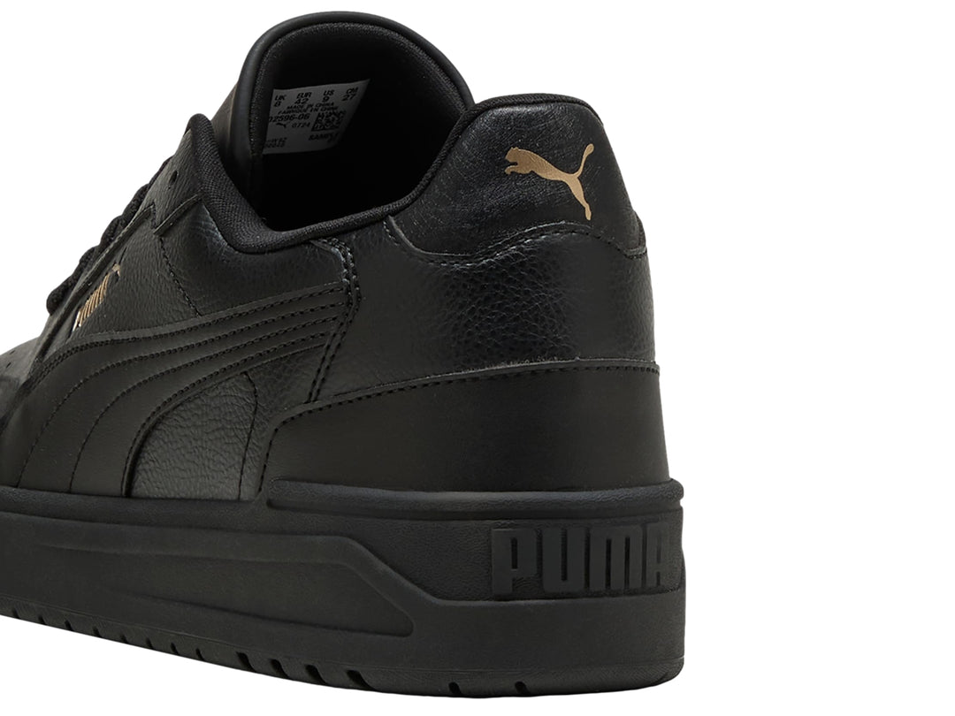 Tenis PUMA Shuffle Downtown color negro con suela gruesa y detalles dorados, vista lateral.