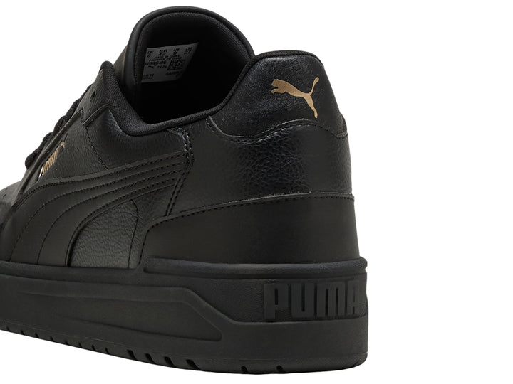 Tenis PUMA Shuffle Downtown color negro con suela gruesa y detalles dorados, vista lateral.