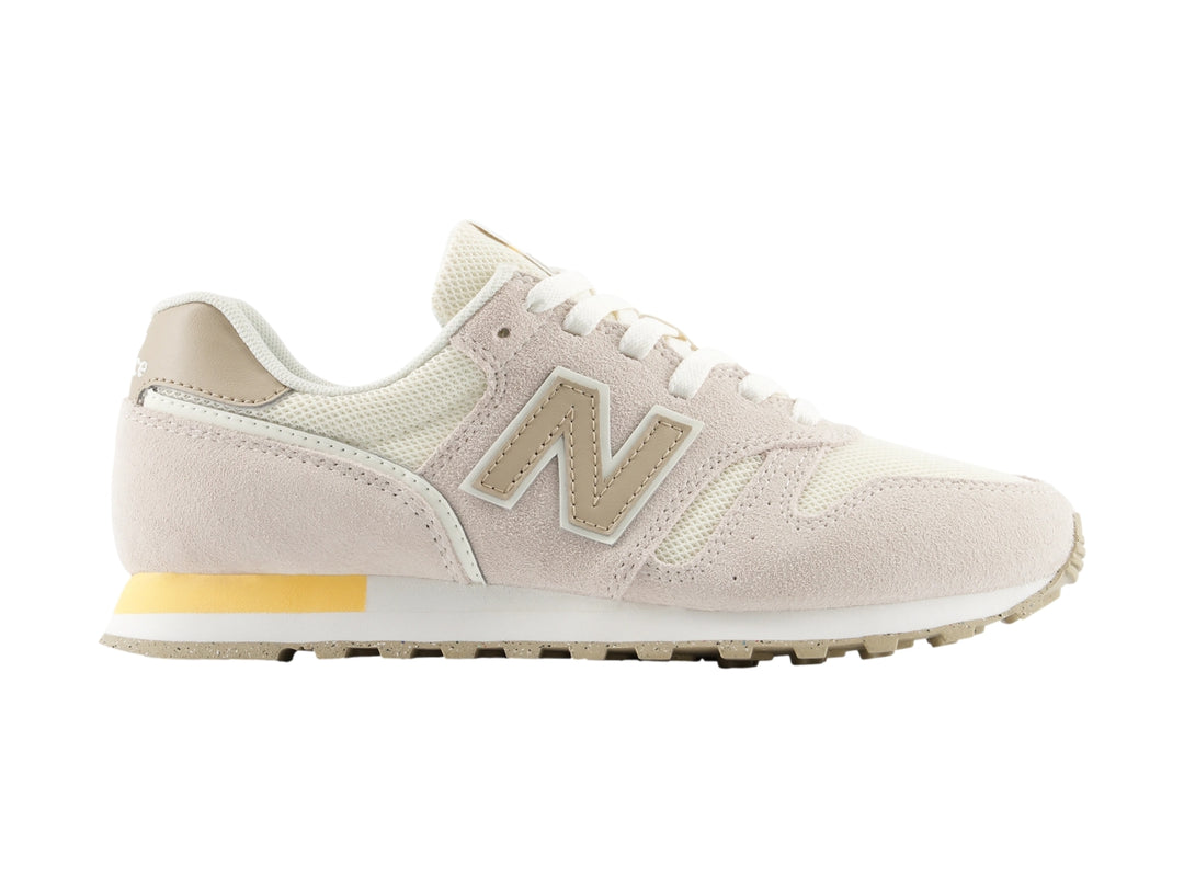 Tenis New Balance color beige con detalles en blanco y amarillo, vista lateral.