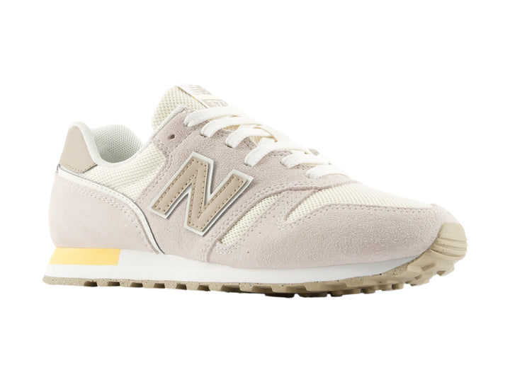 Tenis New Balance color beige con detalles en blanco y amarillo, vista lateral.
