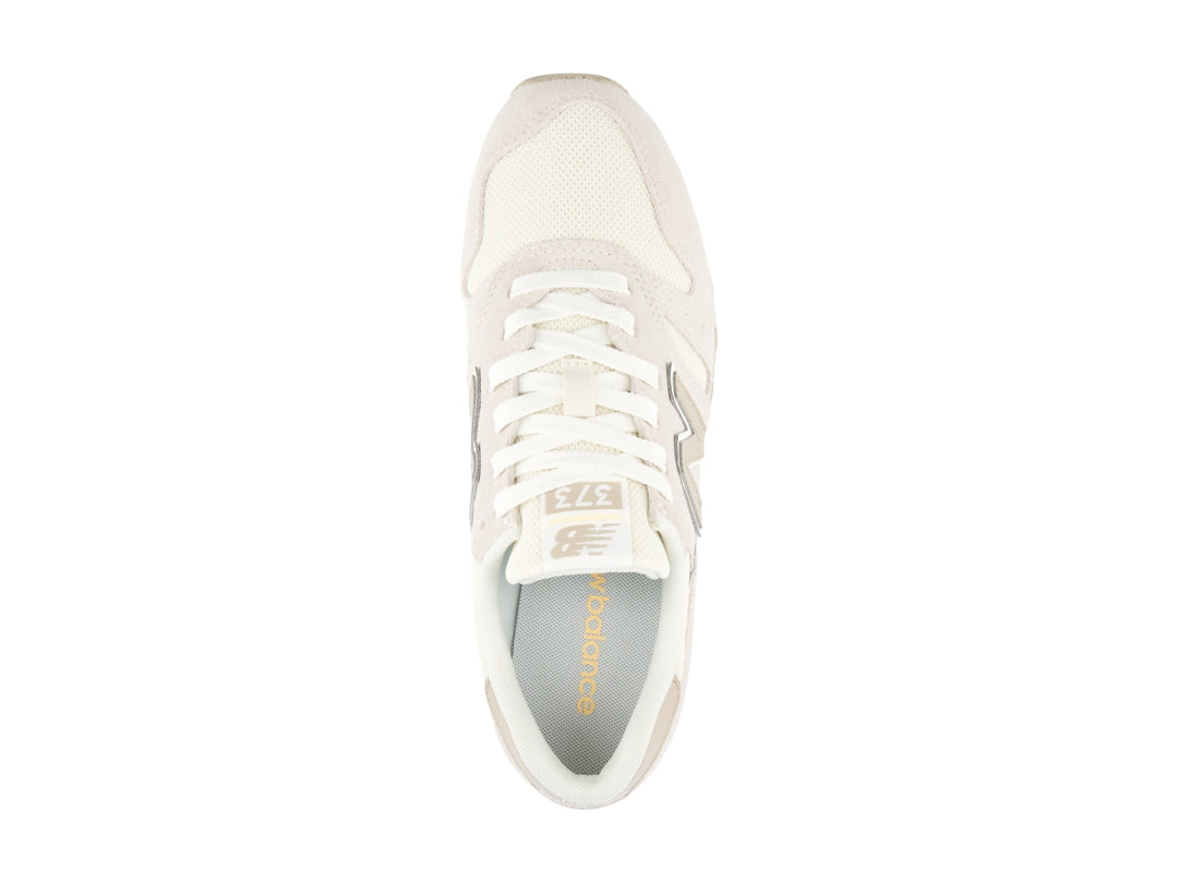 Tenis New Balance color beige con detalles en blanco y amarillo, vista lateral.