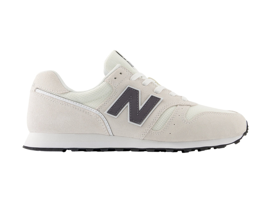 Tenis New Balance color gris con suela blanca y detalles en malla y gamuza.