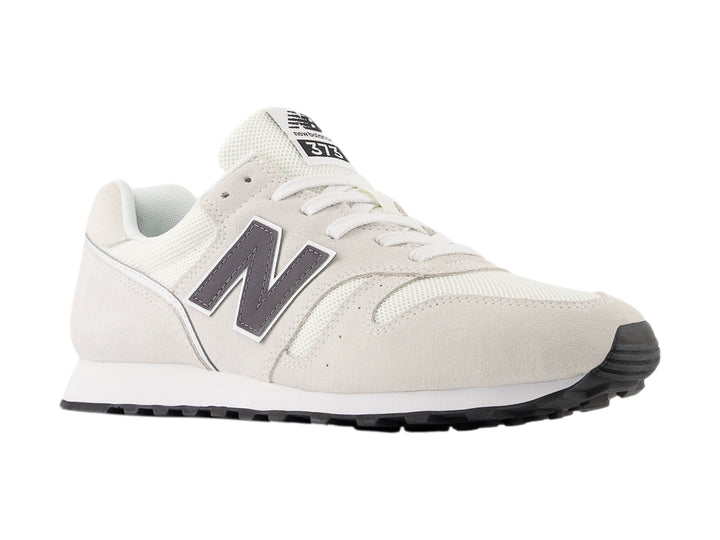 Tenis New Balance color gris con suela blanca y detalles en malla y gamuza.