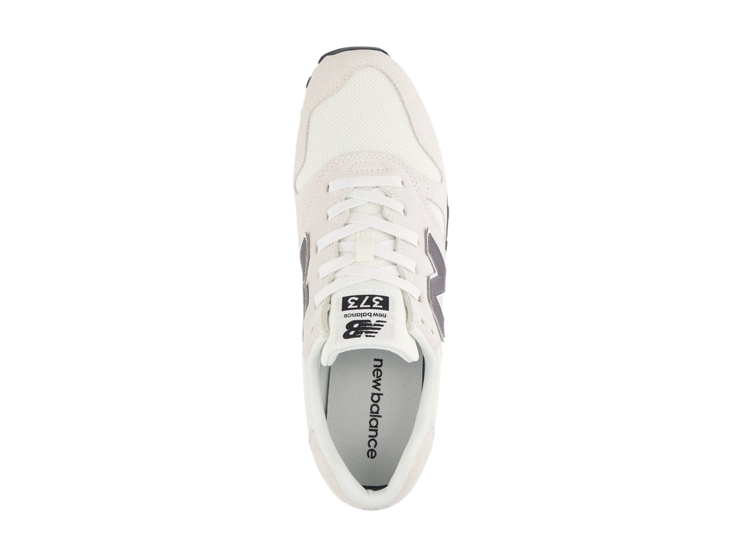 Tenis New Balance color gris con suela blanca y detalles en malla y gamuza.