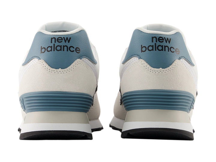 Tenis New Balance 574 para mujer en color gris claro con detalles en azul y suela blanca.