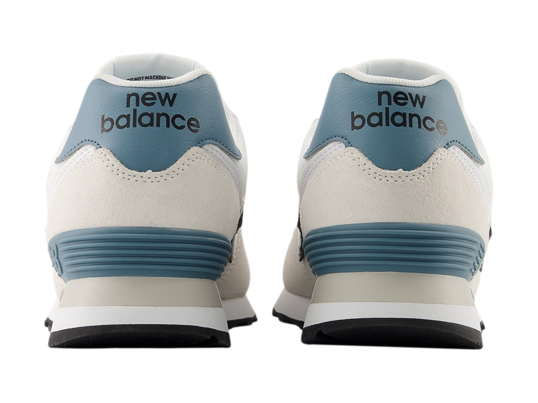 Tenis New Balance 574 color gris claro con detalles en azul y suela blanca para hombre.