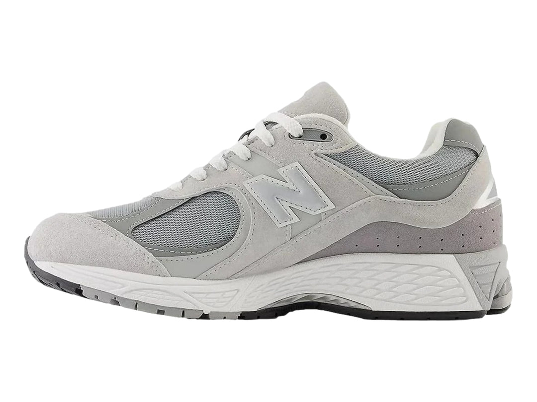 Tenis New Balance 2002RX color gris para mujer con detalles en malla y suela amortiguada.