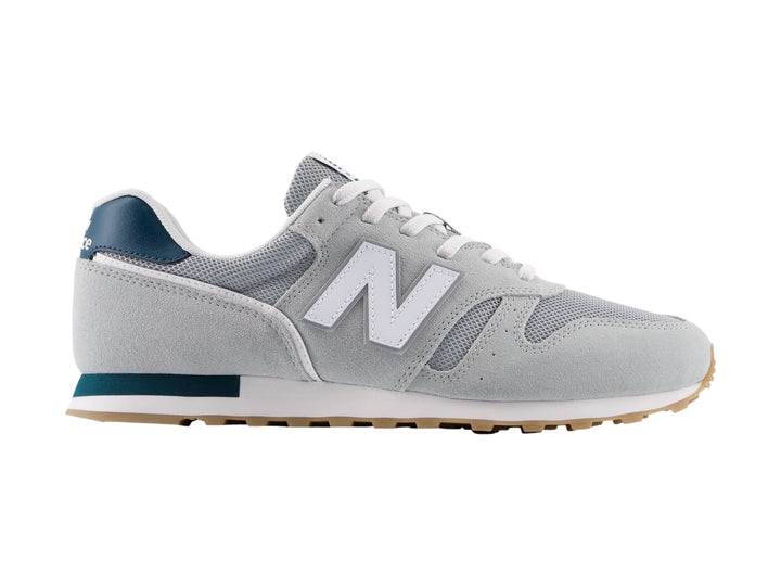 Tenis New Balance modelo 373 en color gris con detalles en blanco y azul marino, vista lateral.