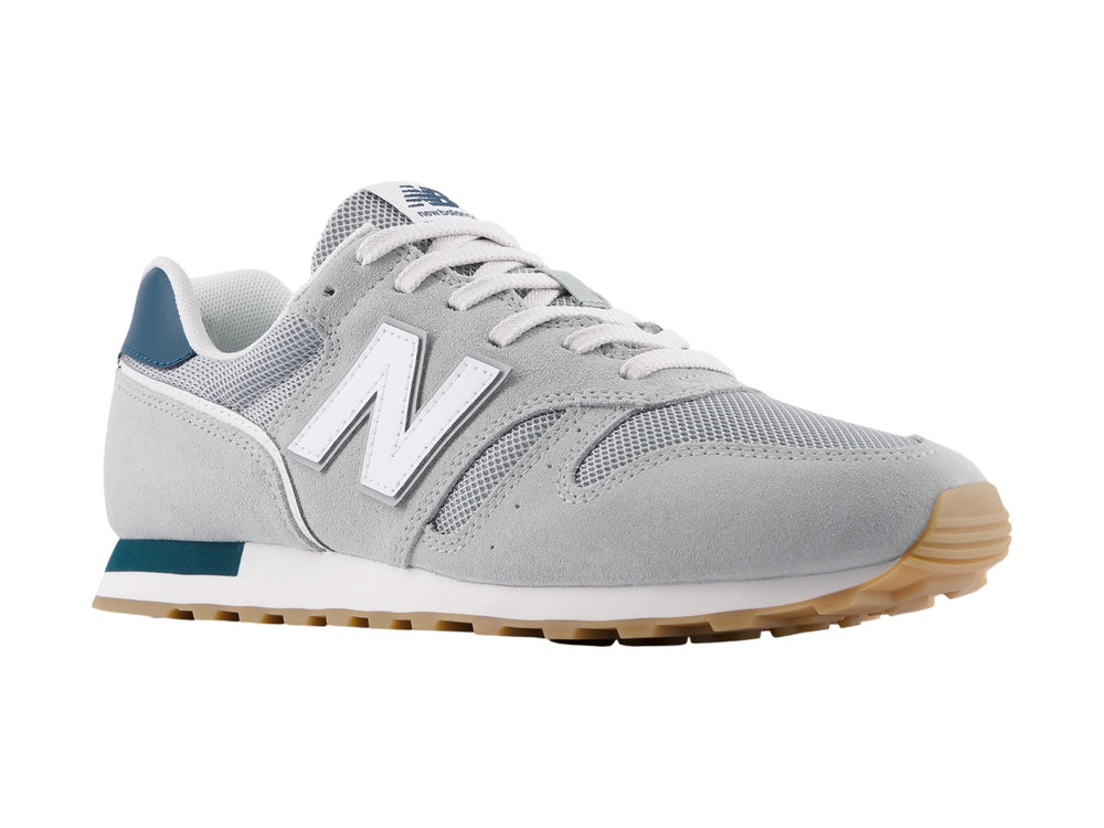 Tenis New Balance modelo 373 en color gris con detalles en blanco y azul marino, vista lateral.