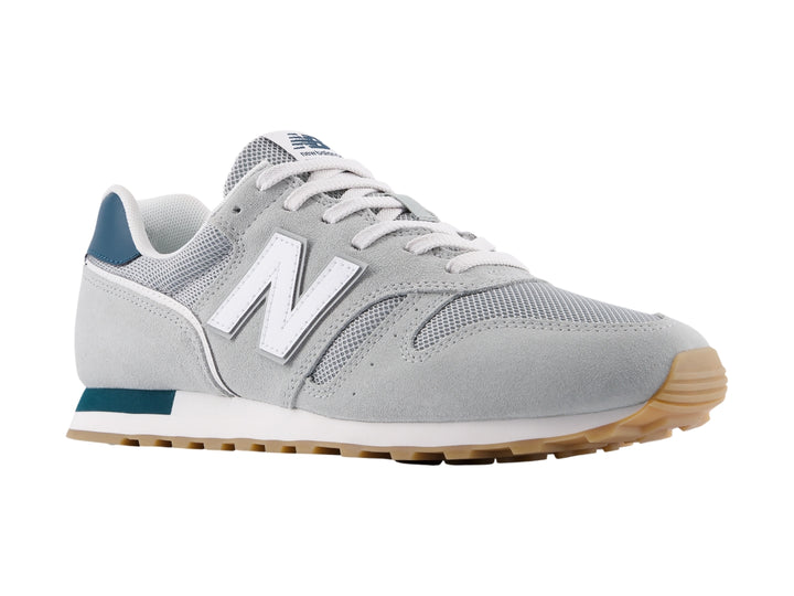 Tenis New Balance modelo 373 en color gris con detalles en blanco y azul marino, vista lateral.