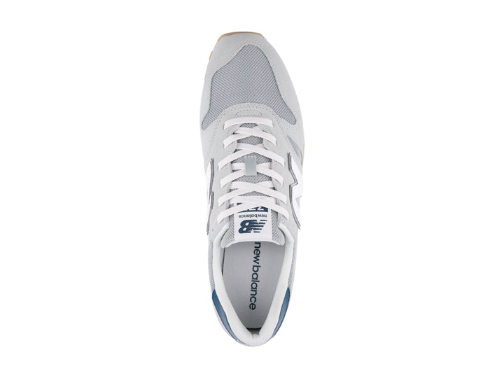 Tenis New Balance modelo 373 en color gris con detalles en blanco y azul marino, vista lateral.