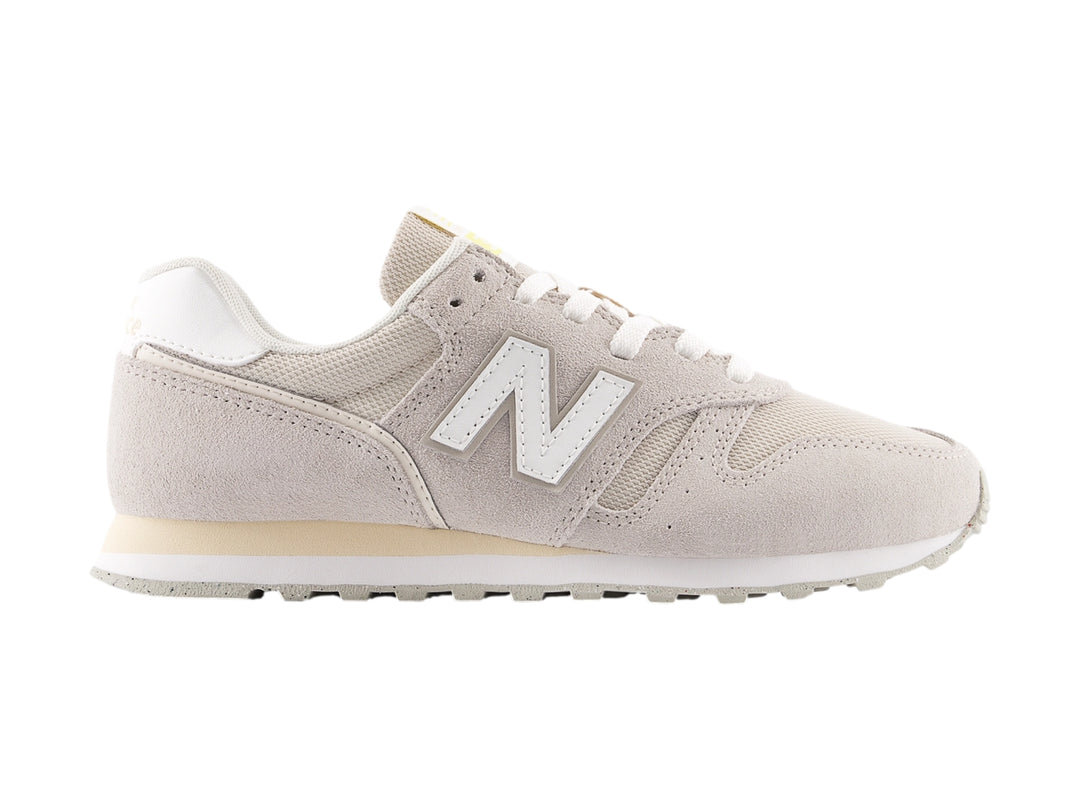 Tenis New Balance color gris con detalles en blanco y suela blanca, vista lateral.