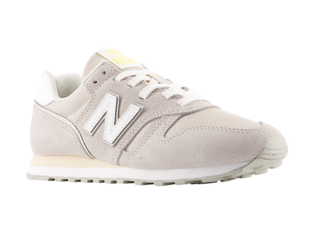 Tenis New Balance color gris con detalles en blanco y suela blanca, vista lateral.