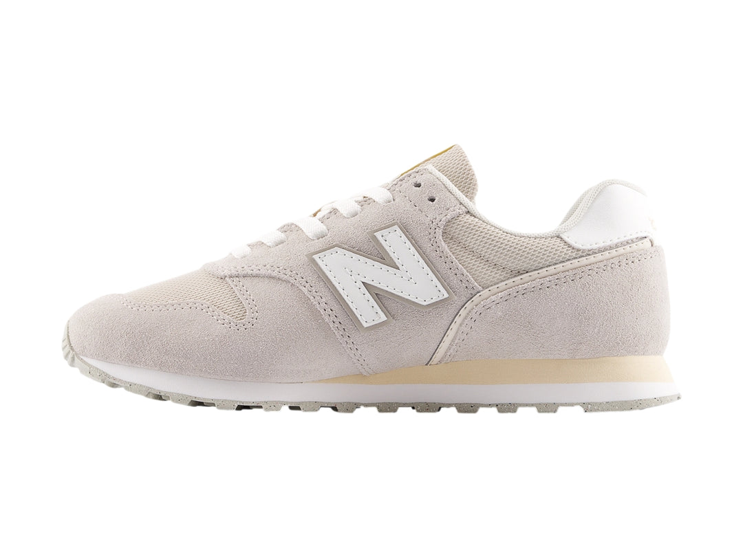 Tenis New Balance color gris con detalles en blanco y suela blanca, vista lateral.
