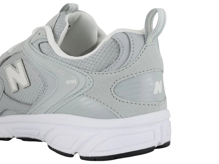 Tenis New Balance modelo 408 en color gris con suela blanca y detalles en malla.