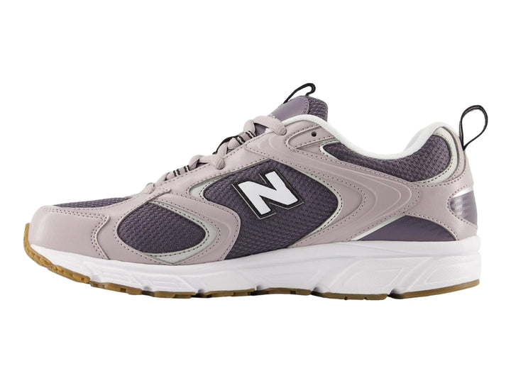 Tenis New Balance 408 color gris con detalles en malla y suela blanca y marrón, vista lateral.