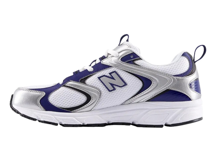 Tenis New Balance blancos con detalles en azul y plata, vista lateral.