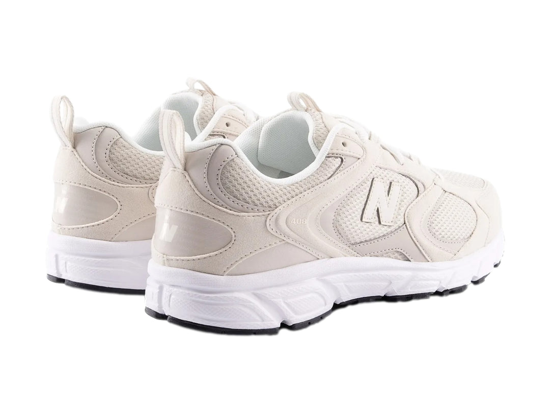 Tenis New Balance color beige y blanco con suela blanca y detalles de malla.