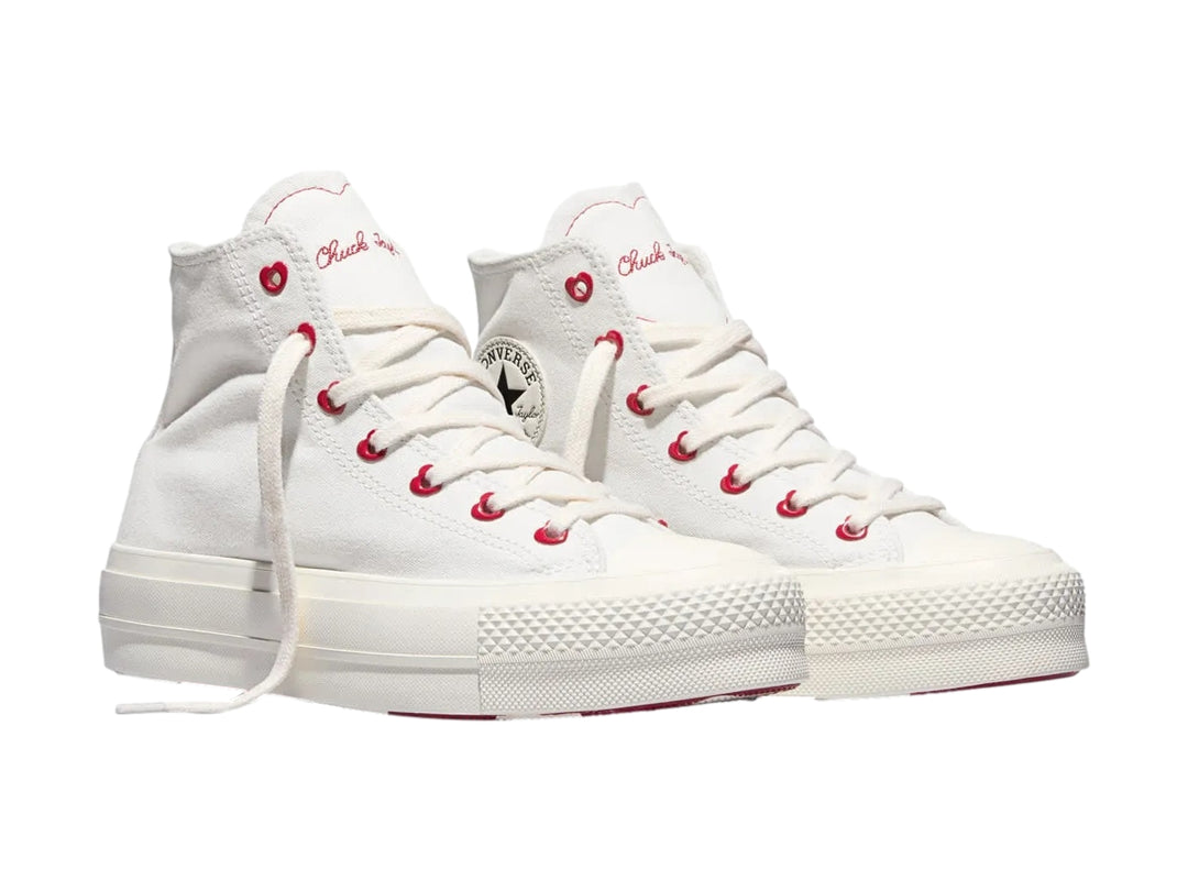 Tenis Converse blancos de bota con plataforma y ojillos rojos en forma de corazón.