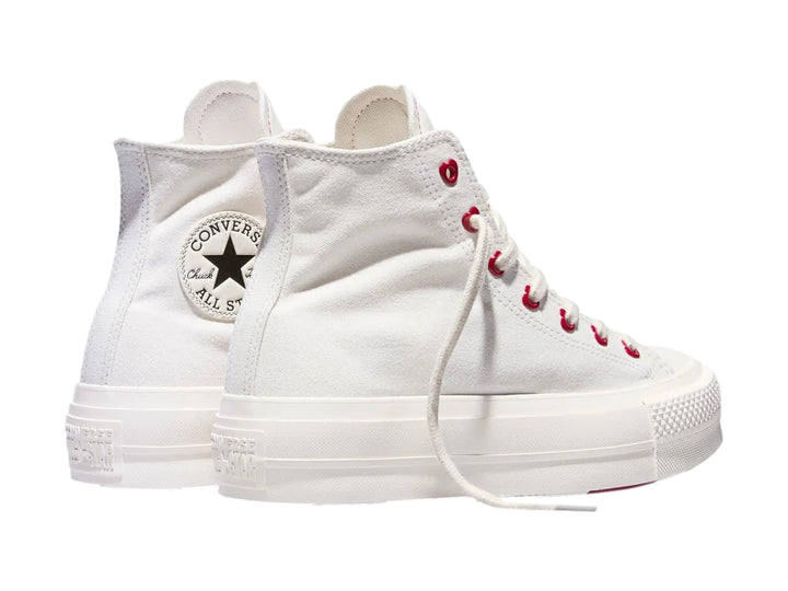 Tenis Converse blancos de bota con plataforma y ojillos rojos en forma de corazón.