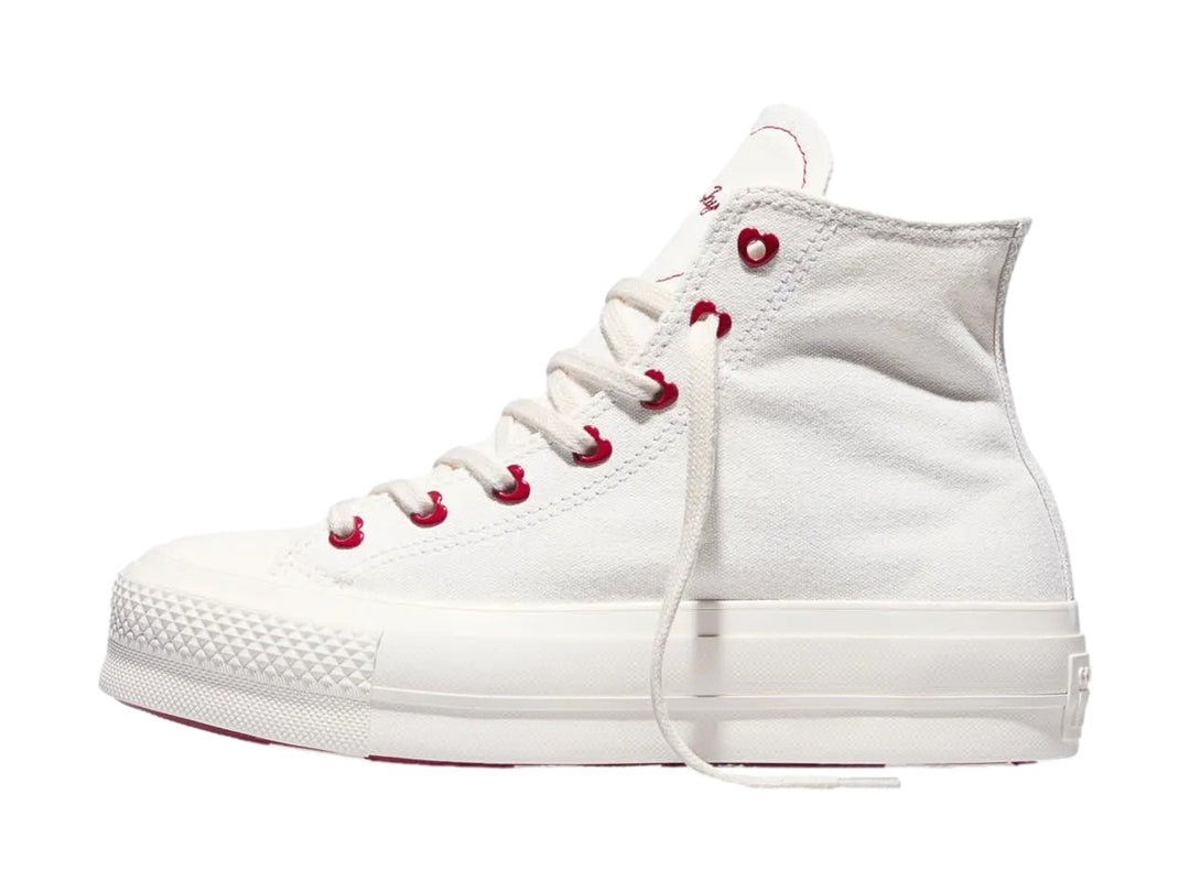 Tenis Converse blancos de bota con plataforma y ojillos rojos en forma de corazón.