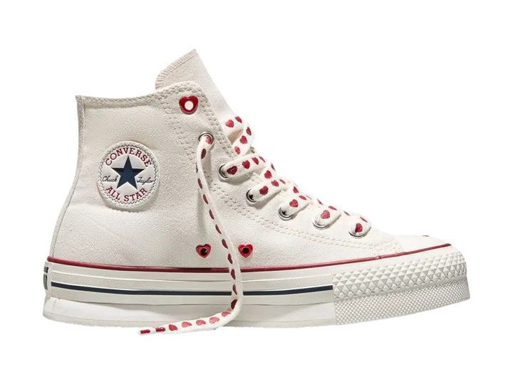 Tenis Converse blancos de bota alta con detalles y agujetas rojas con motivos de corazones.