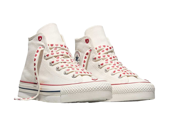 Tenis Converse blancos de bota alta con detalles y agujetas rojas con motivos de corazones.
