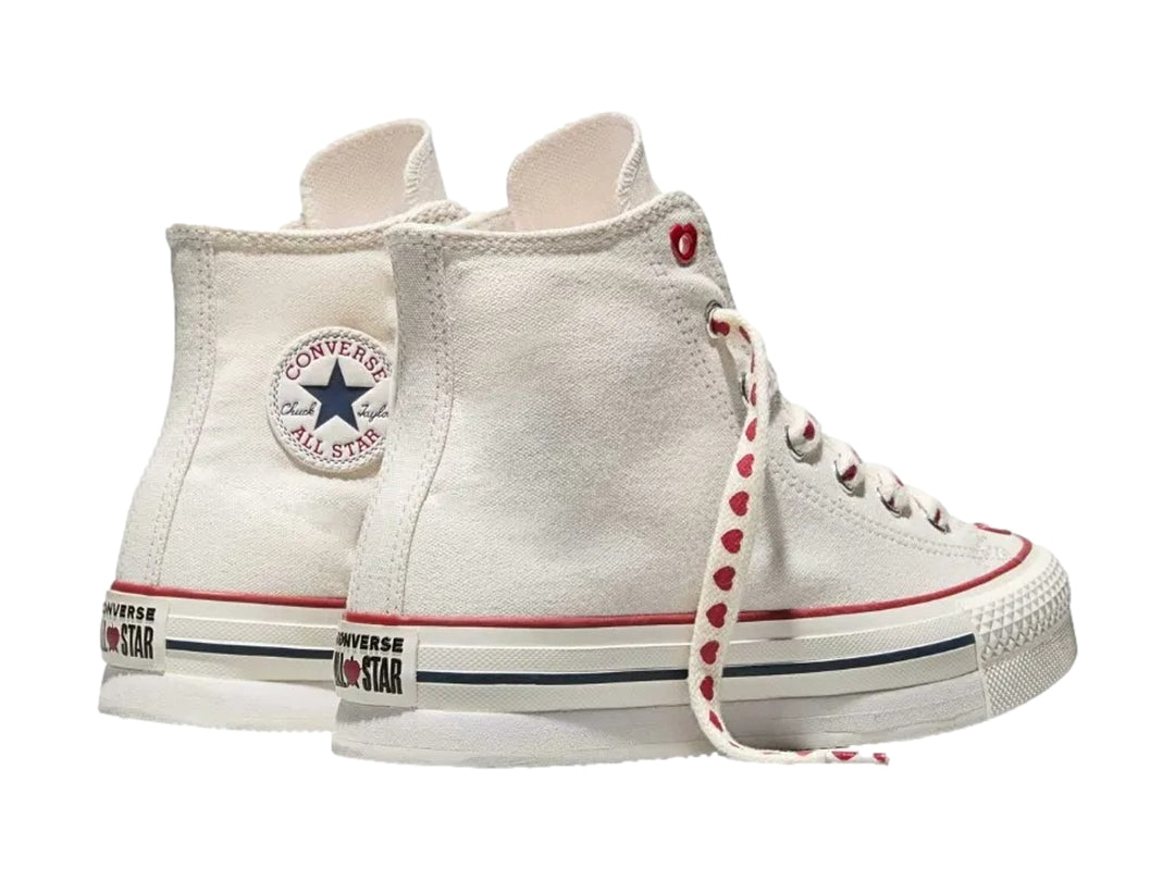 Tenis Converse blancos de bota alta con detalles y agujetas rojas con motivos de corazones.