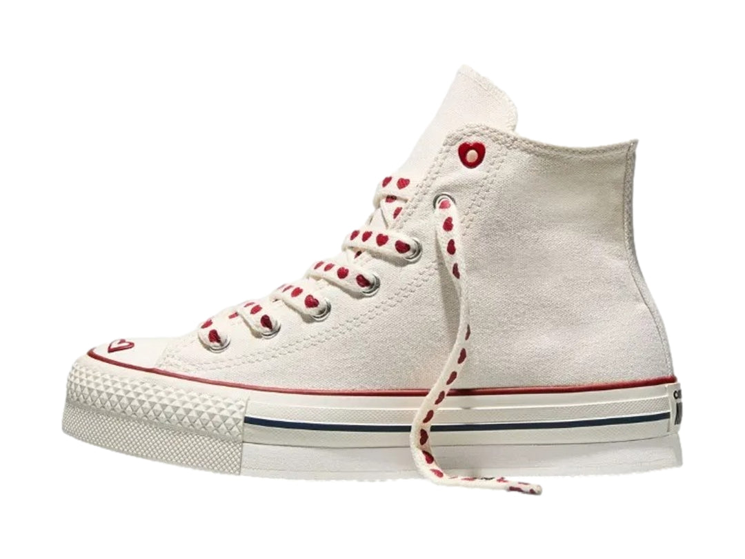 Tenis Converse blancos de bota alta con detalles y agujetas rojas con motivos de corazones.